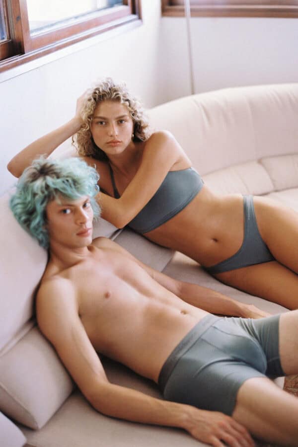 a man and a woman sitting in the couch wearing an organic tencel underwear