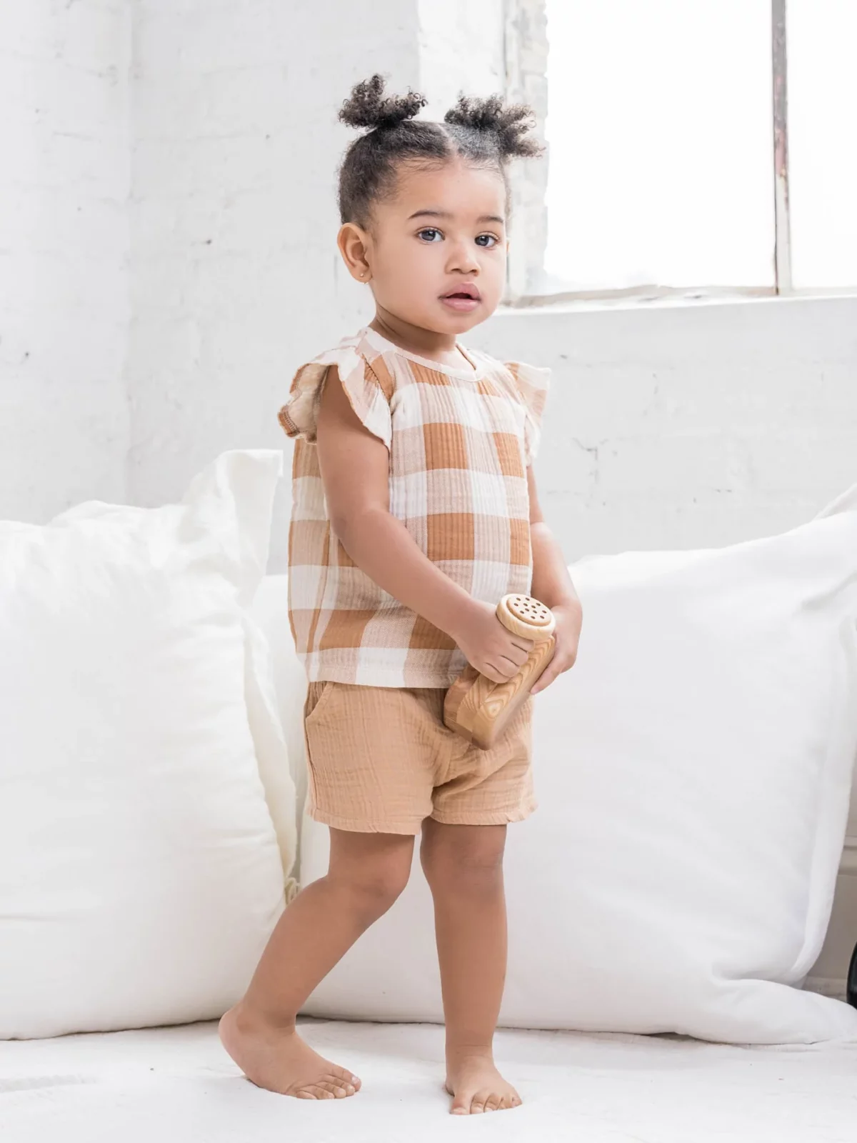 A curly-haired toddler with black hair wearing organic clothes from Colored Organics.