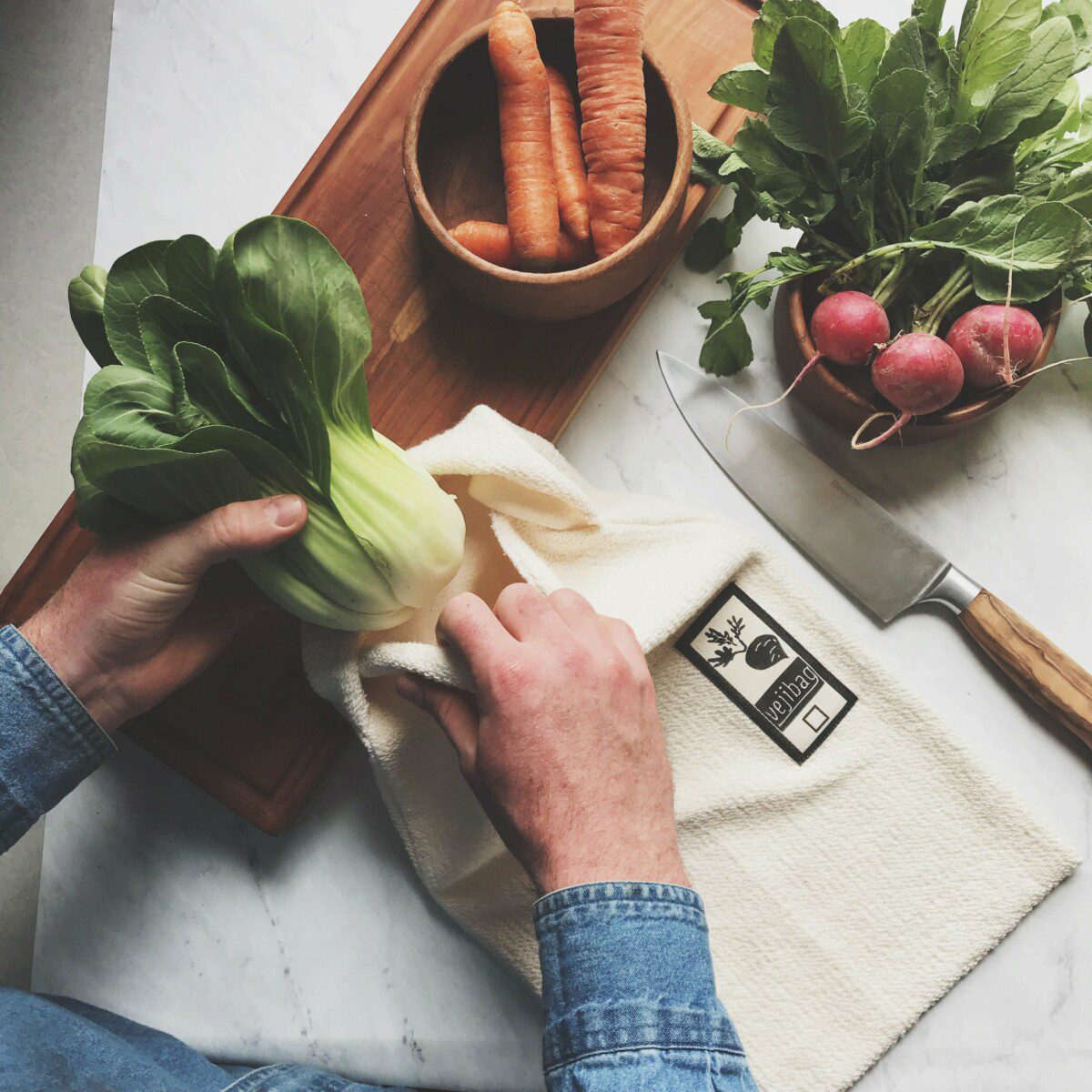 Vejibag plastic-free produce bag with fresh lettuce inside, accompanied by carrots and a knife beside it.