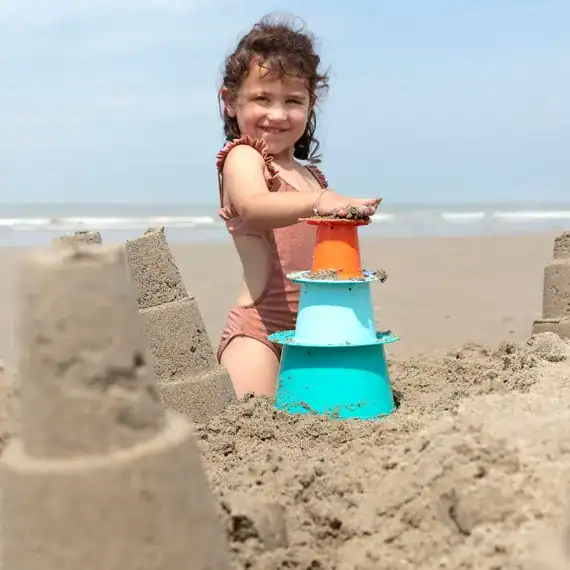 a girl making a sandcastle using a non-toxic beach toy