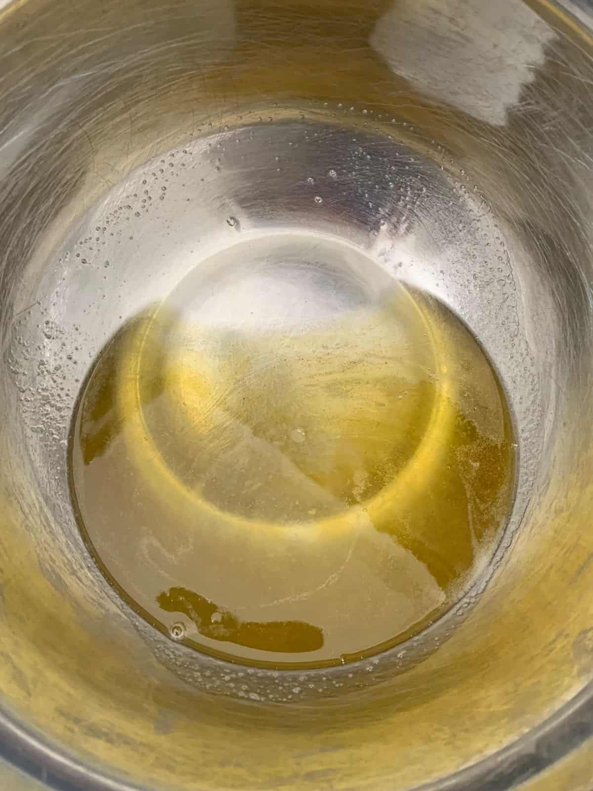 A top-down view shows a silver metal bowl containing a melted cacao butter