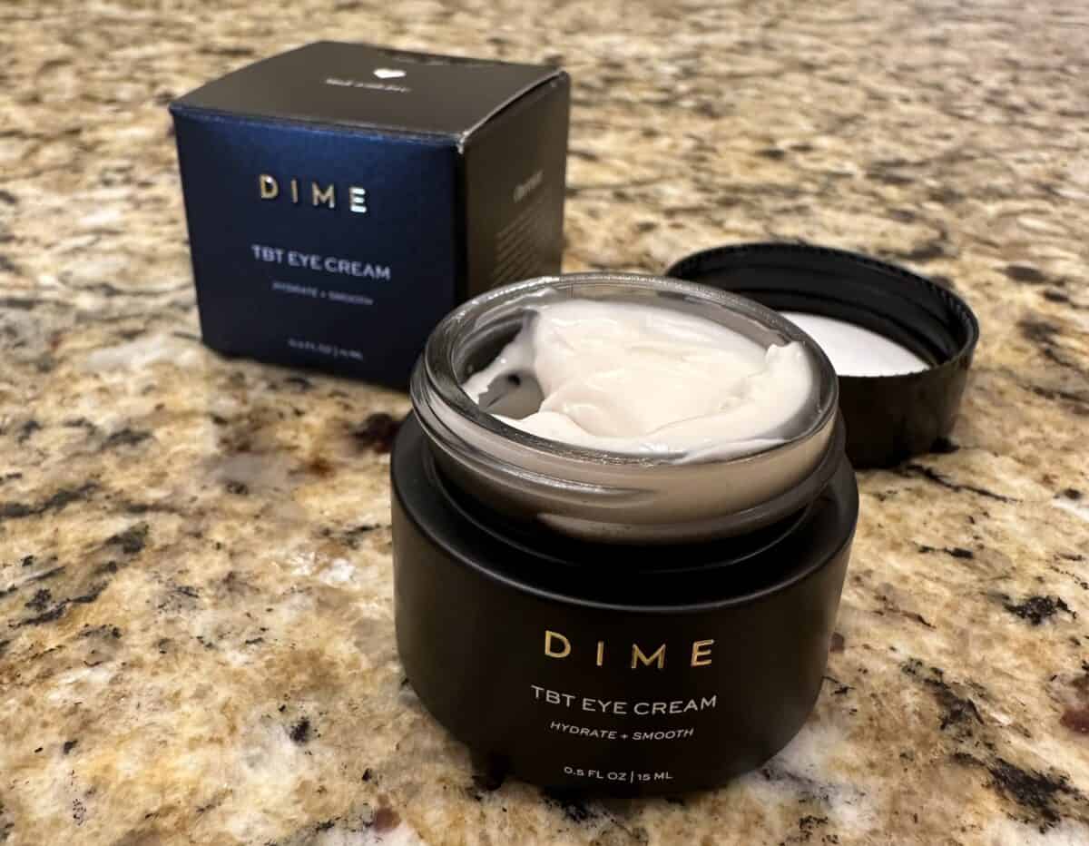Open jar of DIME TBT Eye Cream on a granite countertop with the product box in the background.