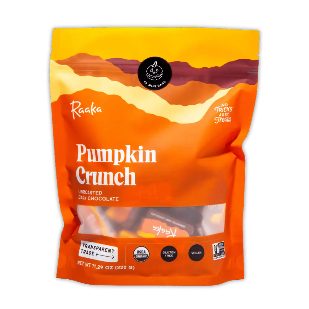 A large orange pouch of Raaka Pumpkin Crunch Unroasted Dark Chocolate is shown against a gray background.