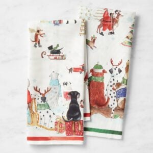 Holiday tea towels featuring playful dog illustrations in winter scenes.