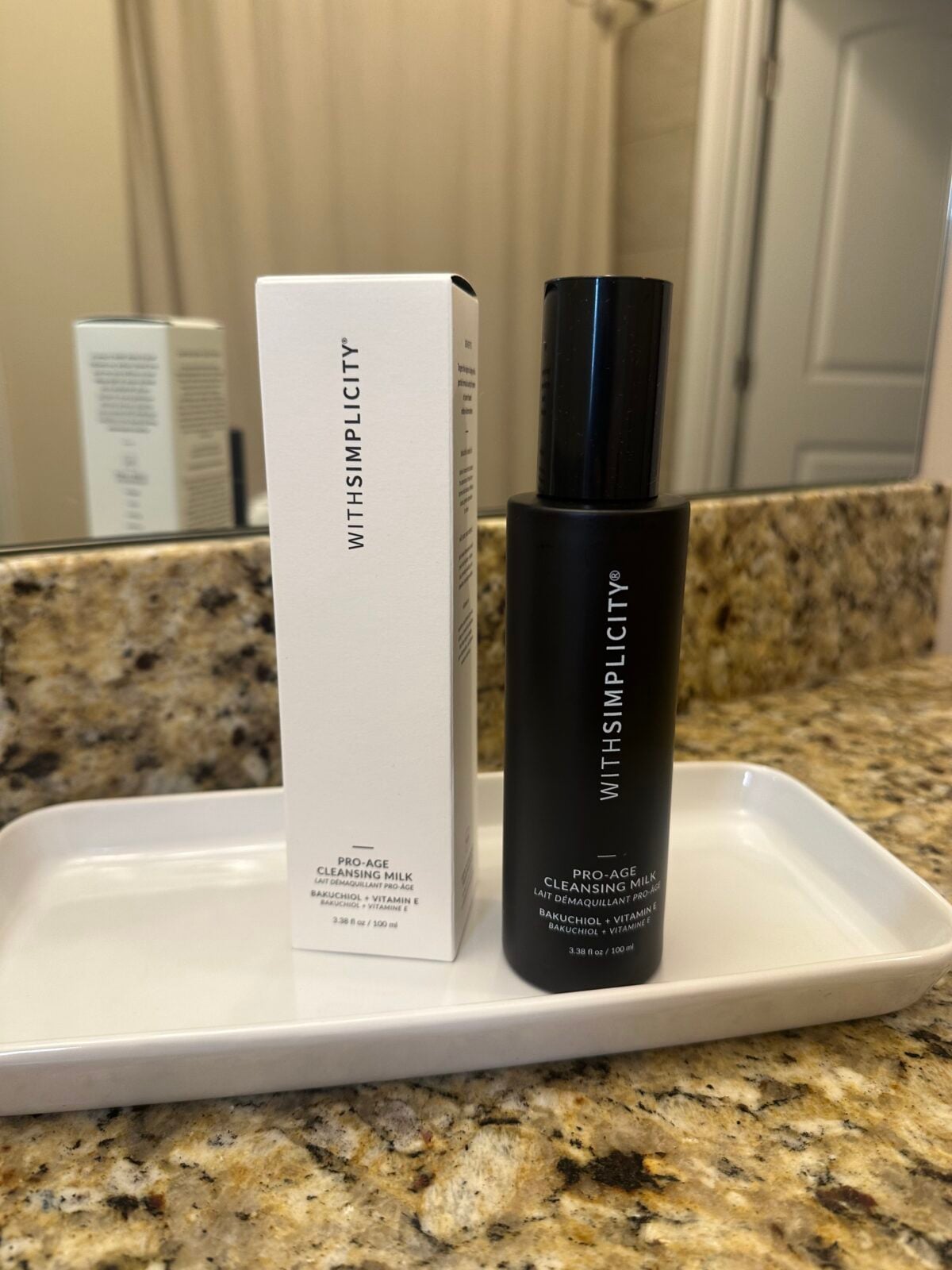 a black bottle and white box of withSimplicity's Pro-Age Cleanser sitting on a granite bathroom counter