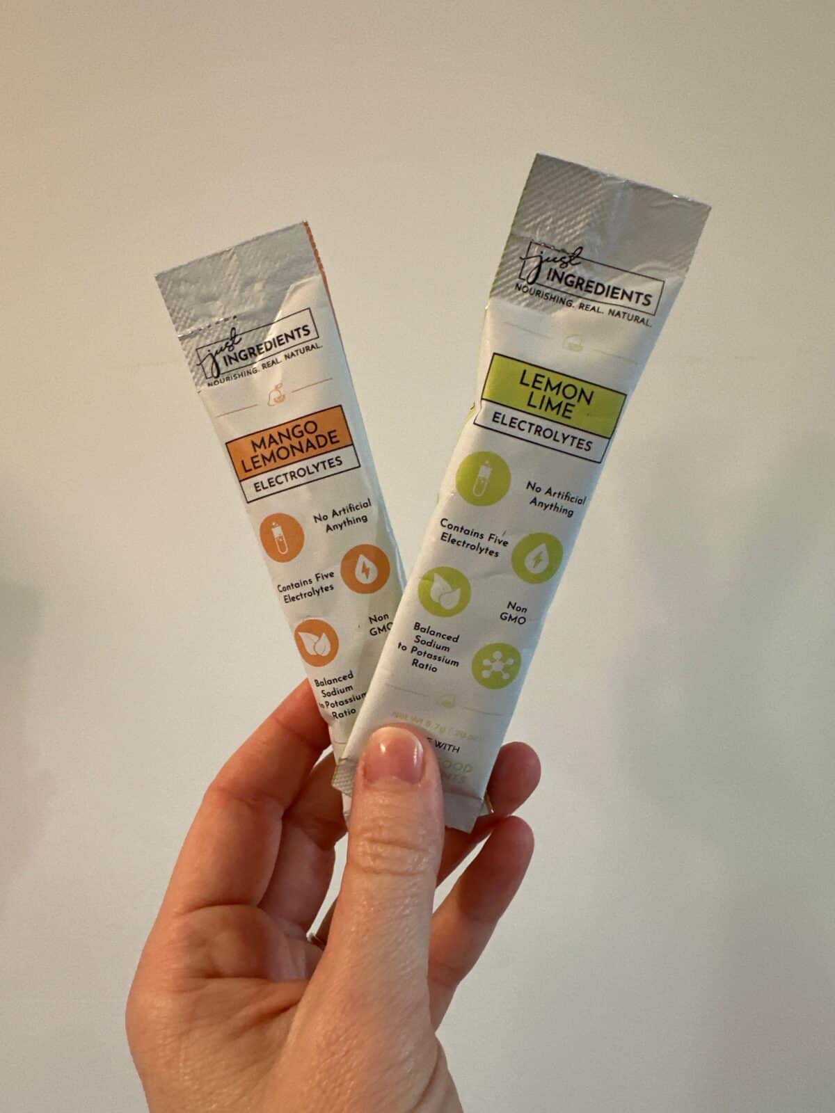 A person displaying two flavors of Just Ingredients Electrolytes.