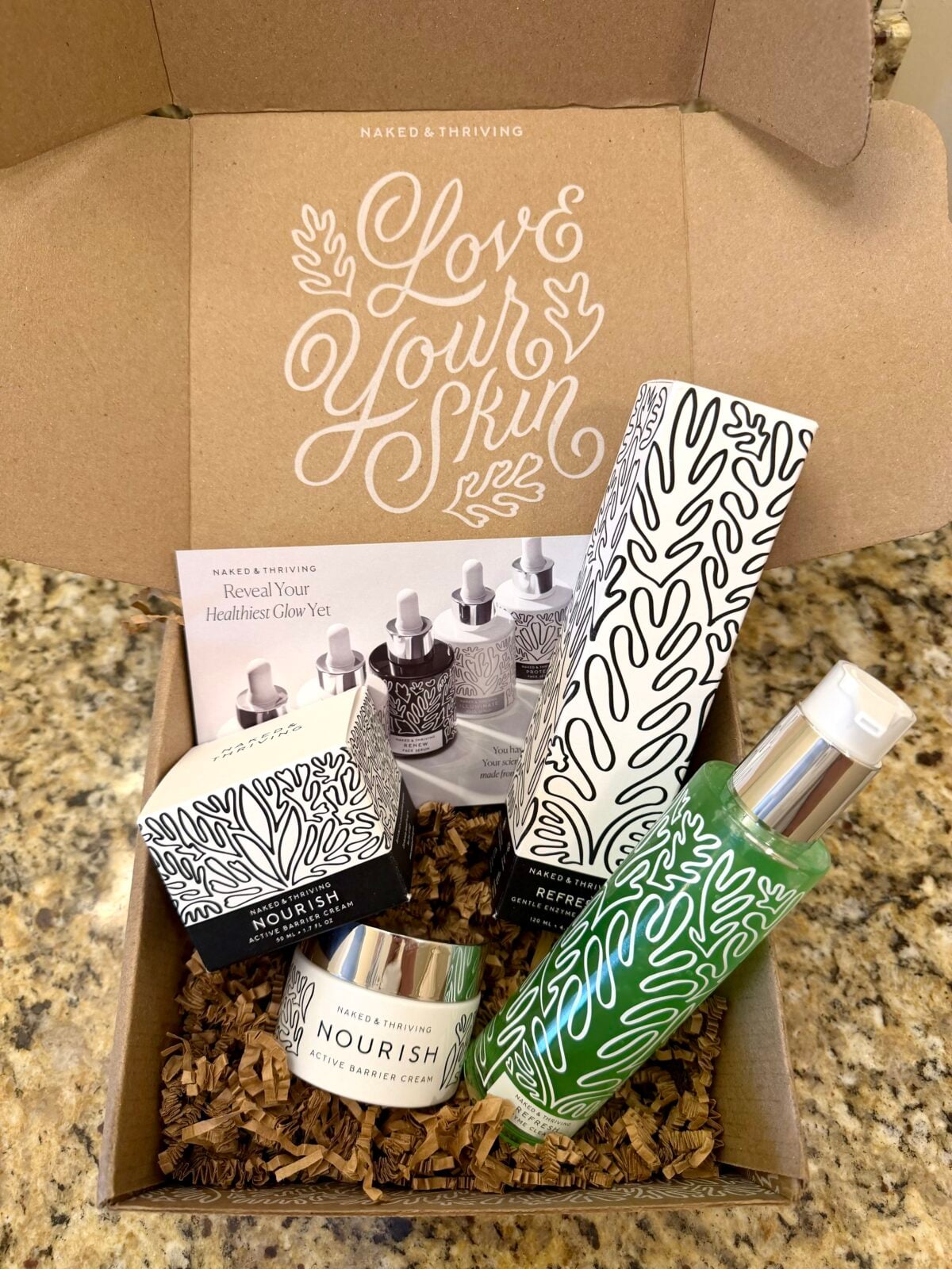 Naked & Thriving skincare gift box with Nourish cream and Refresh cleanser arranged inside branded packaging.