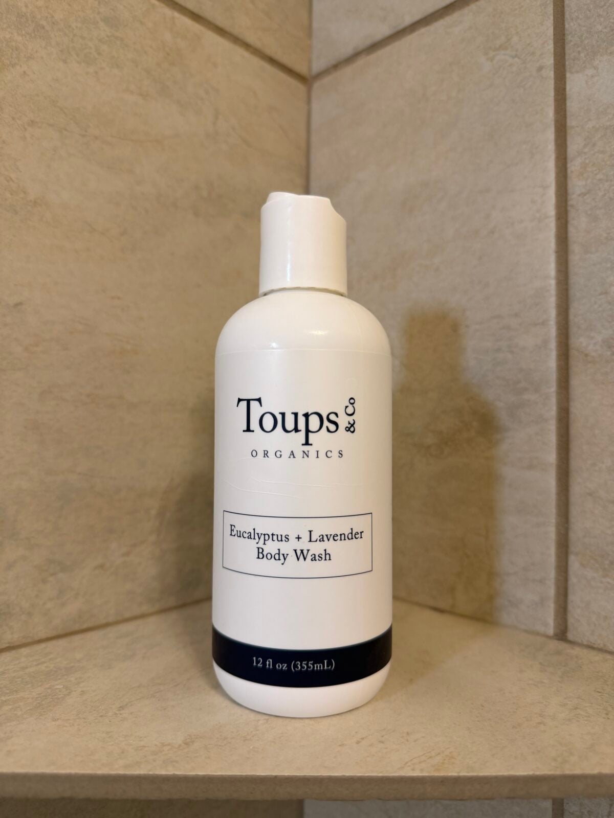 Toups & Co Organics Eucalyptus + Lavender Body Wash bottle on a tiled shower shelf