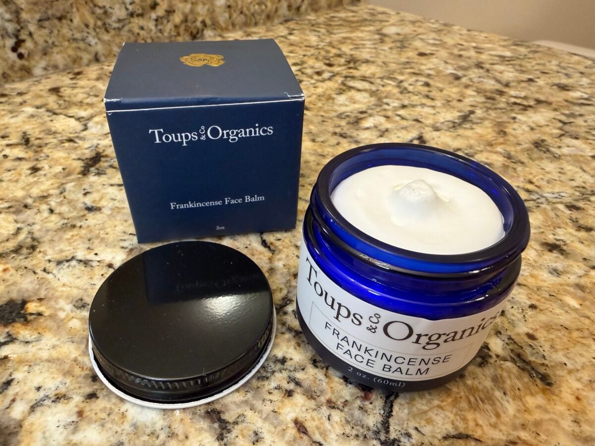 Toups & Co Organics Frankincense Face Balm in a blue glass jar with lid and box on a bathroom countertop.