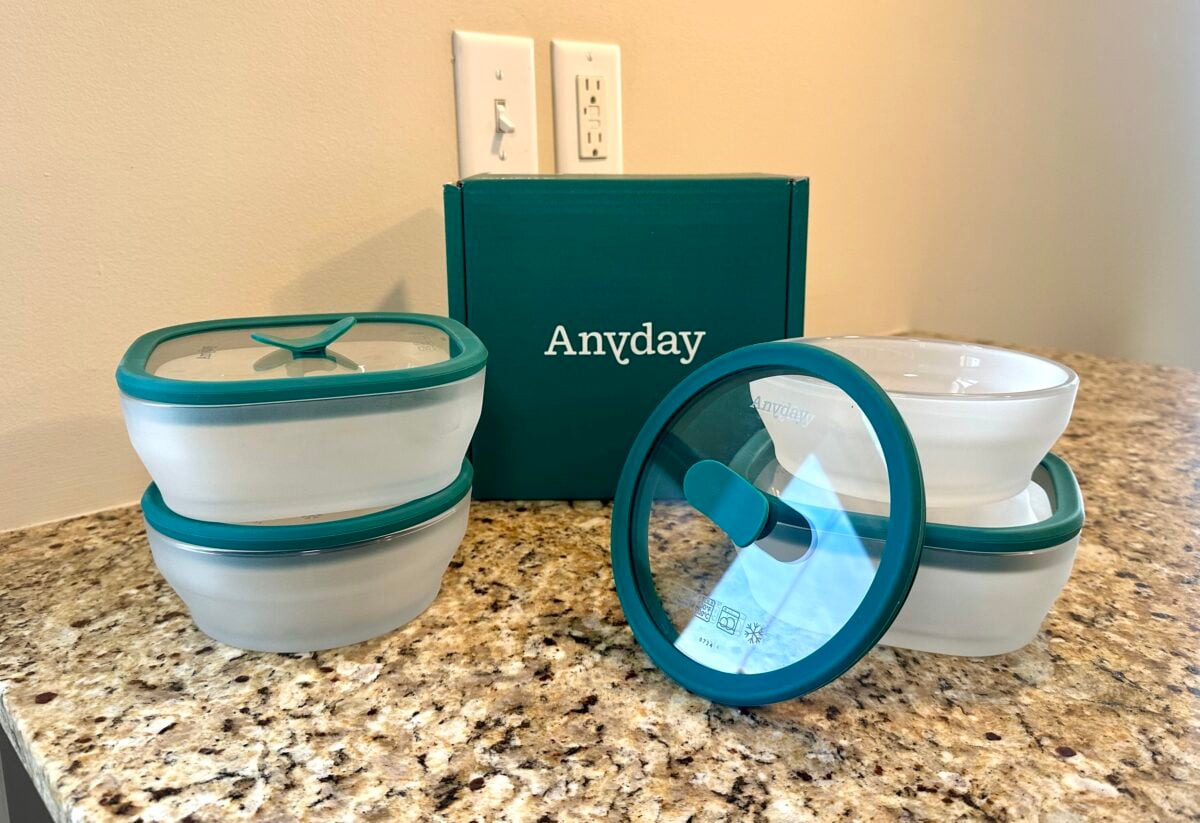 Anyday glass food storage containers with teal lids arranged on a granite countertop, with the teal Anyday box in the background.