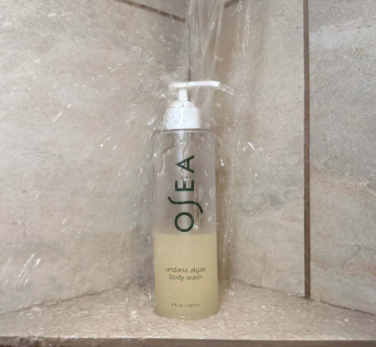 OSEA undaria algae body wash bottle with pump dispenser on a shower tile ledge