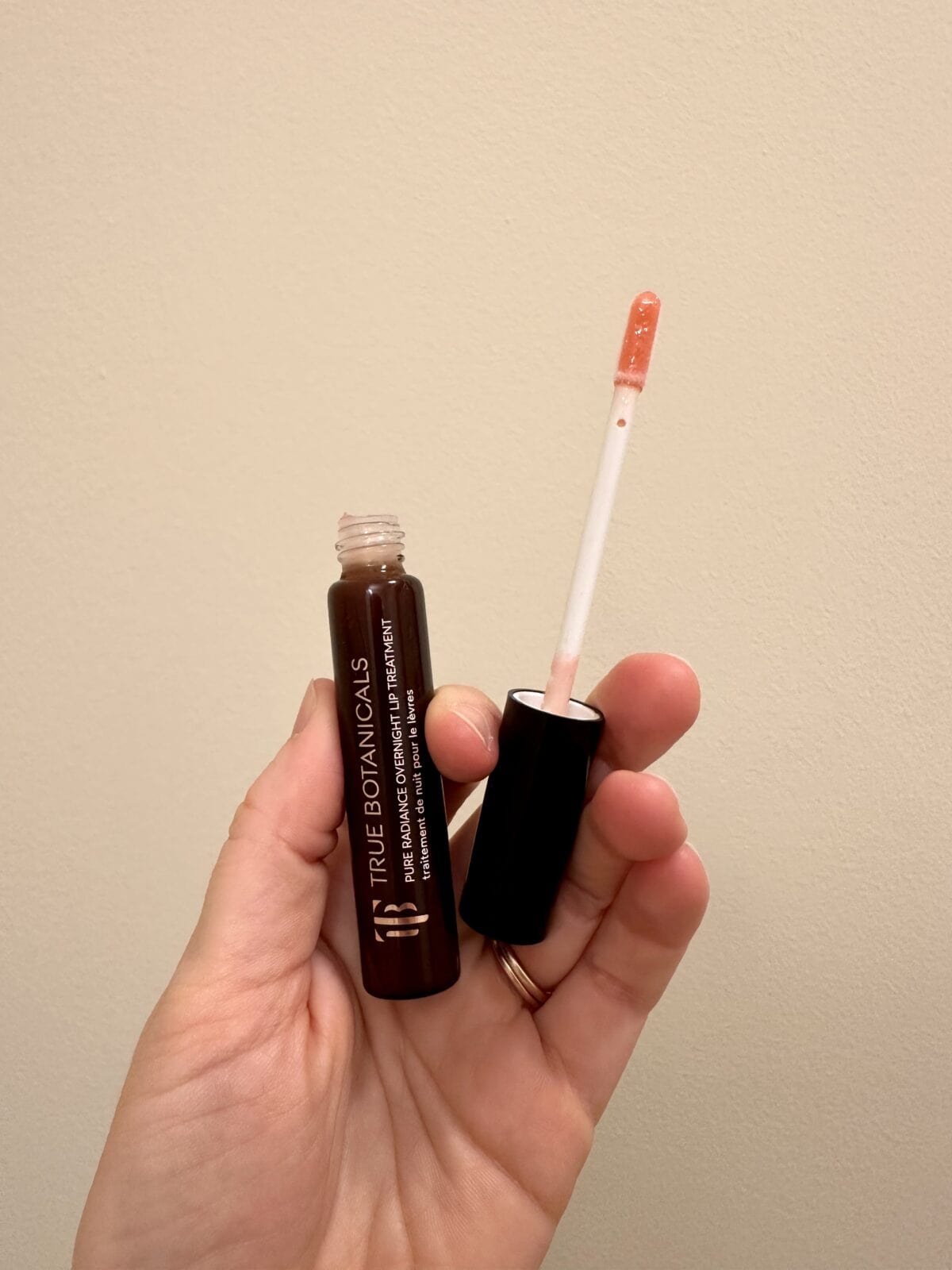 a hand holding the Pure Radiance Overnight Lip Treatment from True Botanicals