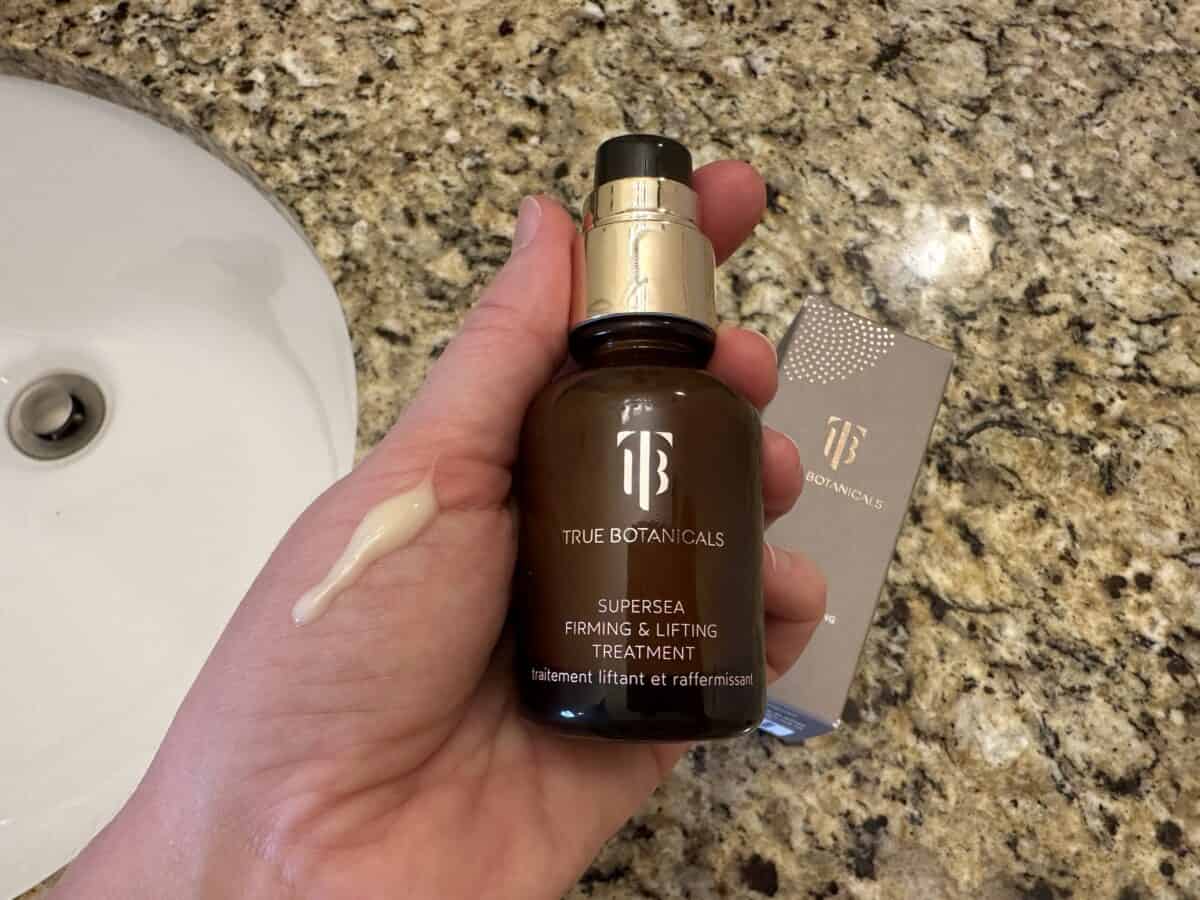 The photo shows a hand holding the Supersea Firming & Lifting Treatment from True Botanicals with its box