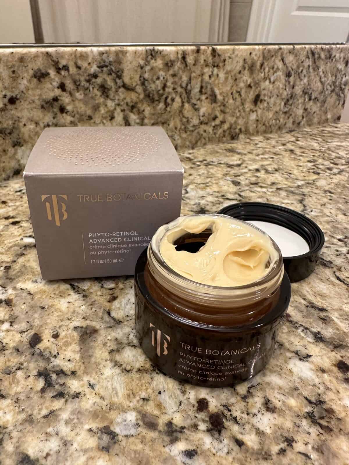 The photo shows the Phyto-Retinol Advanced Clinical Cream from True Botanicals with its box arranged on a granite countertop with a bathroom mirror in the background.