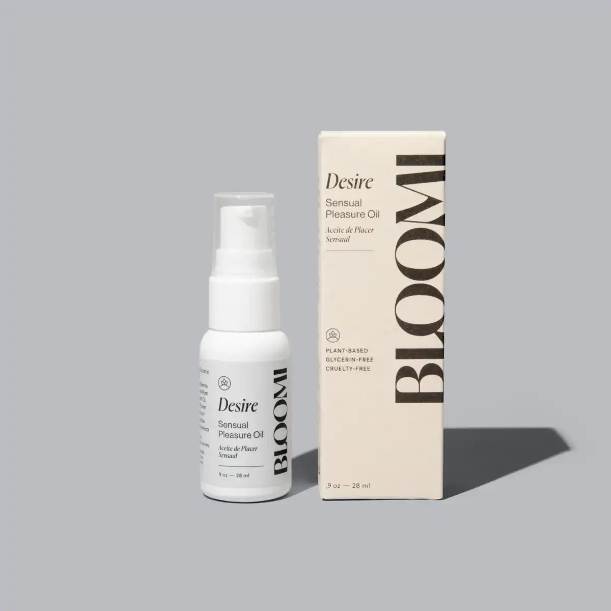 A bottle of Bloomi Desire Sensual Pleasure Oil is shown next to its tall, rectangular box on a solid gray background.