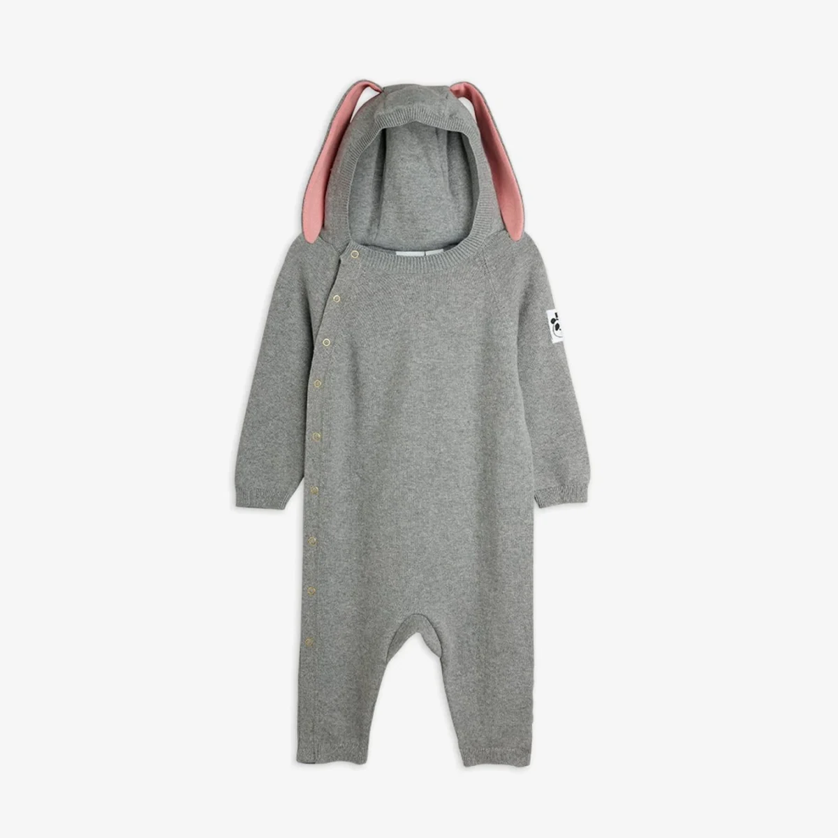 Gray baby onesie with long sleeves and legs, featuring a hood with pink inner bunny ears. There are snap buttons running diagonally across the front and a white patch on the left sleeve. The suit is laid flat on a white background.