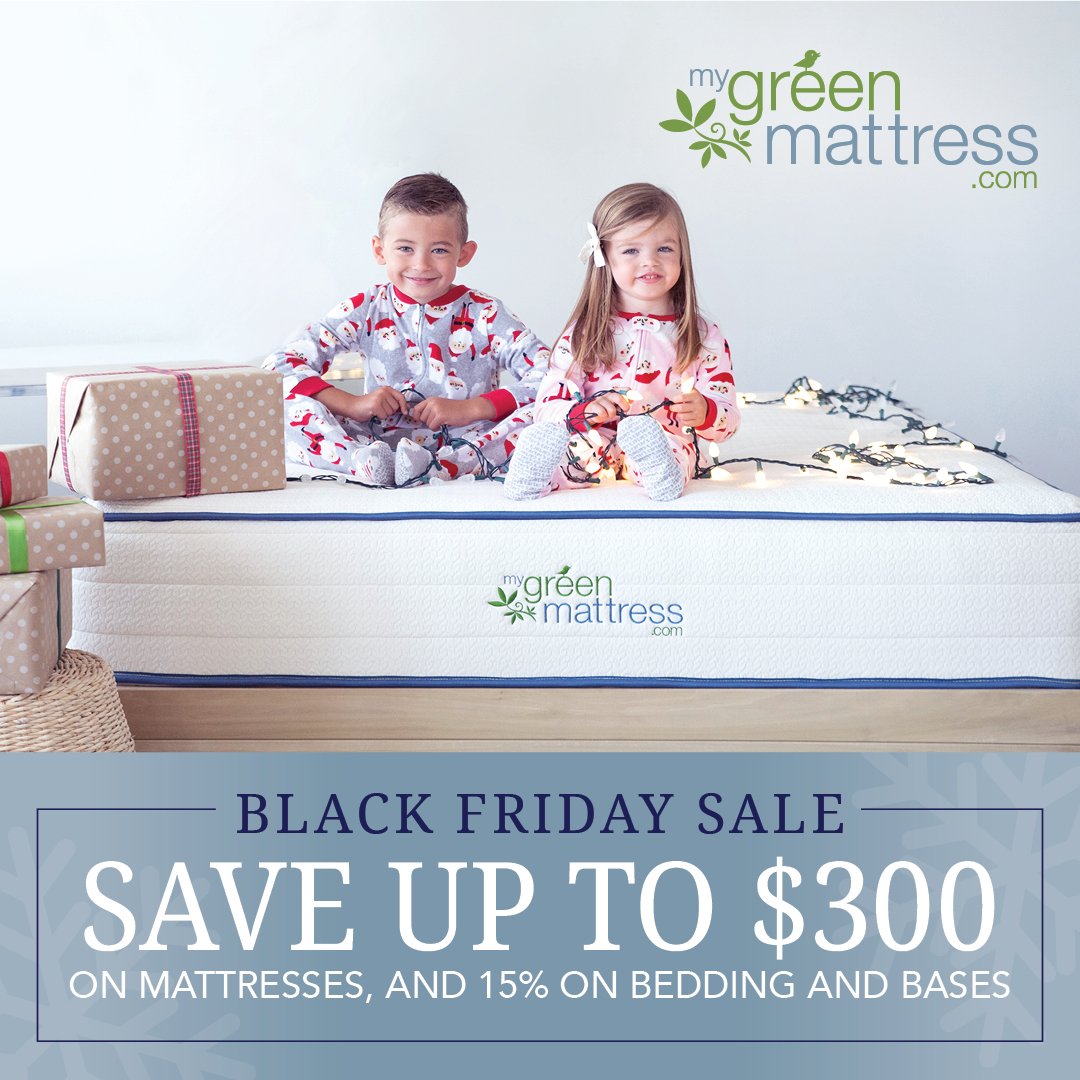 Two children in holiday pajamas sit on a My Green Mattress bed surrounded by wrapped gifts and string lights, with text promoting a Black Friday sale offering up to $300 off mattresses and 15% off bedding and bases.