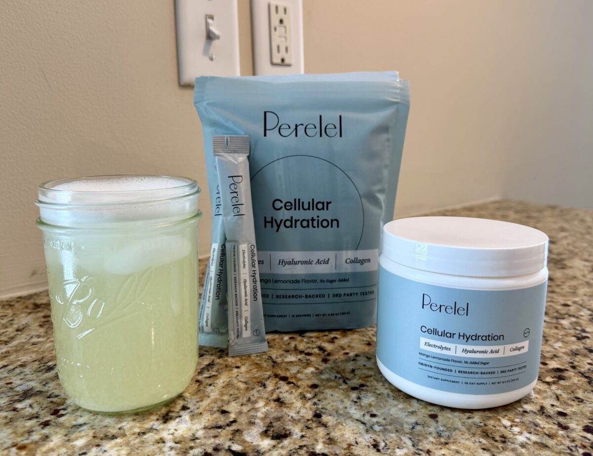 A glass jar filled with a light yellow drink sits on a kitchen counter next to Peretel Cellular Hydration powder packets, a resealable pouch, and a white tub, all labeled with the same product branding.