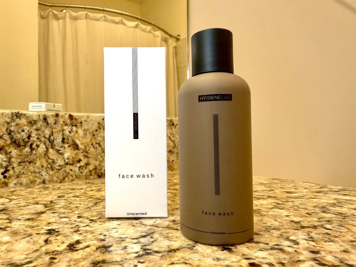 The photo features an unscented "face wash" from the brand Hygiene Lab, shown as a matte-brown bottle next to its white packaging on a speckled granite countertop.