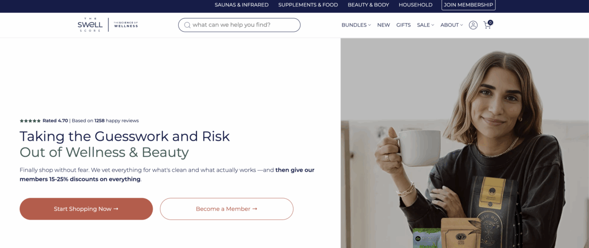 A woman sits at a table holding a white mug, smiling at the camera. On the table in front of her are several supplements or wellness product packages. The website header and navigation menu are visible above.