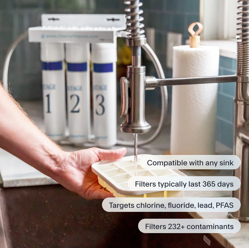 The image shows a person filling an ice cube tray from a kitchen faucet equipped with a three-stage Clearly Filtered under-sink water filtration system, highlighting key features like its 365-day filter life and ability to target over 232 contaminants.