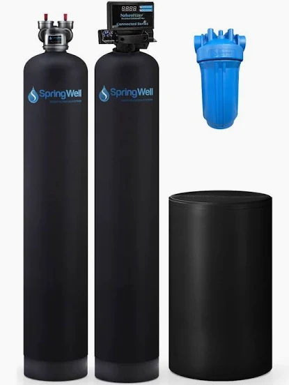 The image displays a SpringWell whole-house water filtration and salt-based softener system, featuring two tall black tanks, a smaller black brine tank, and a blue pre-filter housing.