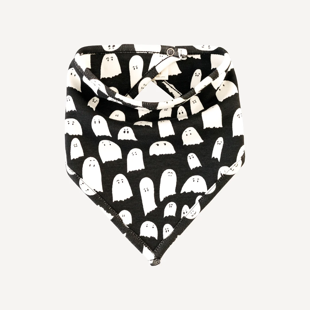 A black bandana bib featuring a pattern of white cartoon ghost shapes with simple facial expressions, arranged in rows. The bib is fastened with metal snaps at the back.