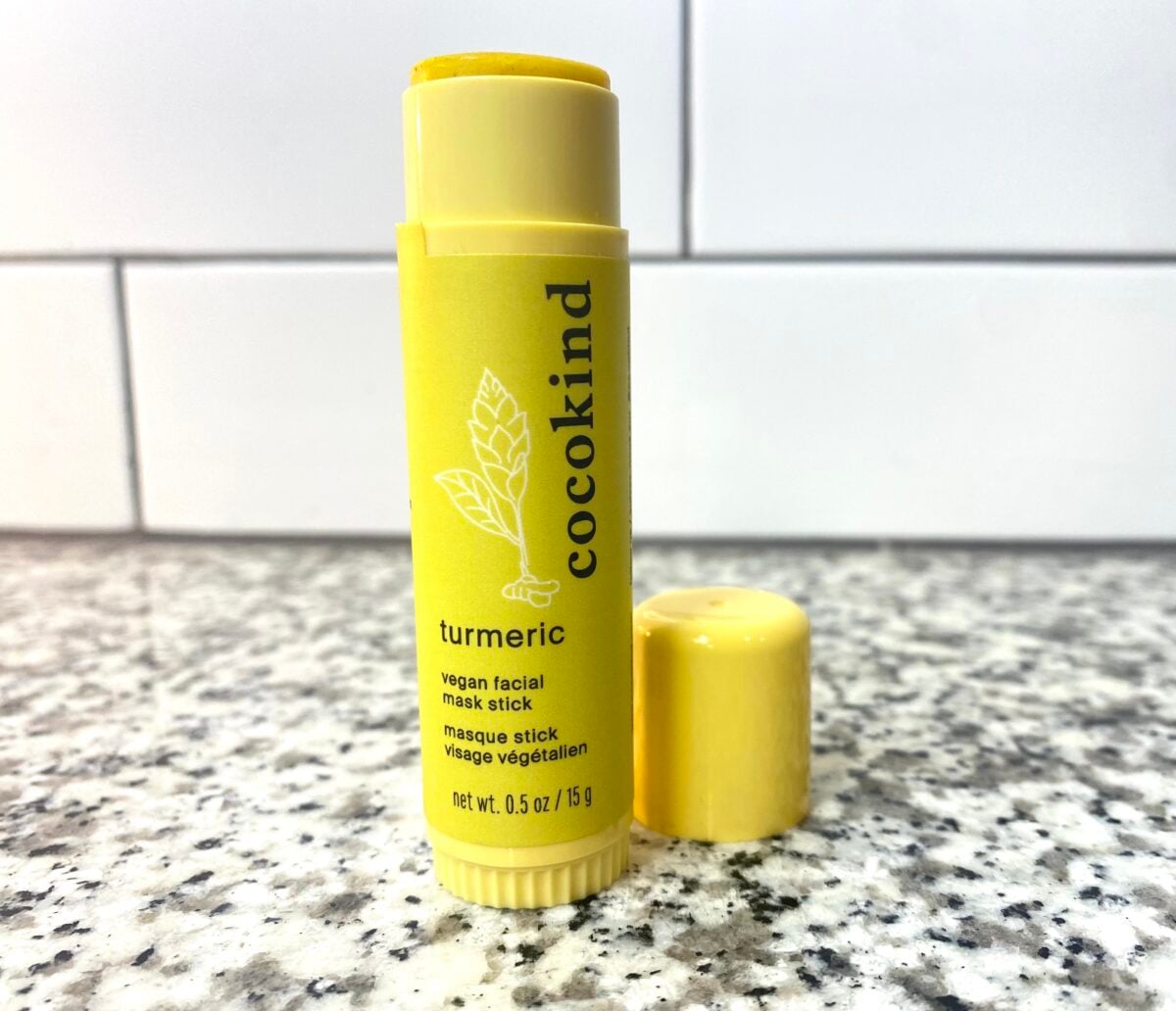 A yellow Cocokind turmeric vegan facial mask stick with its cap removed.