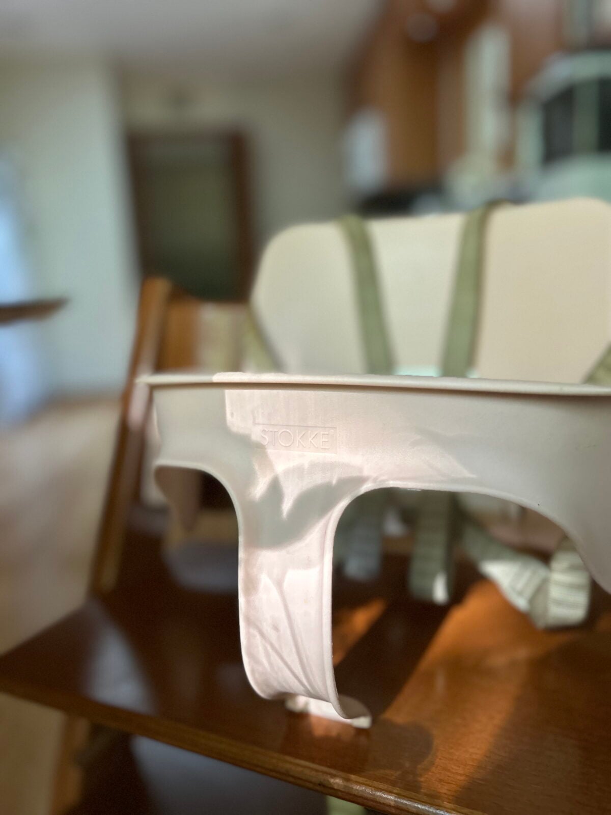 Stokke brand high chair tray attachment on a wooden high chair.